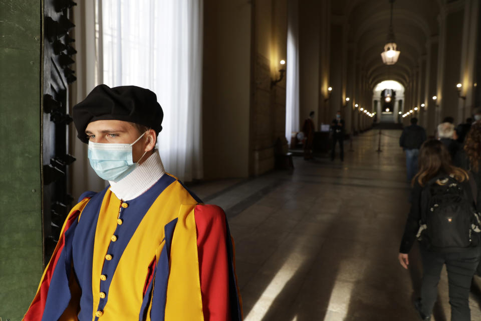 A Vatican Swiss guard wears a face mask to prevent the spread of COVID-19 as faithful arrive to attend Pope Francis' general audience, the first with faithful since February when the coronavirus outbreak broke out, in the San Damaso courtyard at the Vatican, Wednesday, Sept. 2, 2020. (AP Photo/Andrew Medichini)