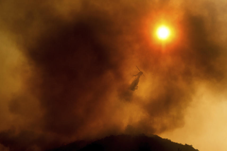 FILE - In this Monday, Aug. 17, 2020 file photo, a helicopter drops water while battling the River Fire in Salinas, Calif. Fire crews across the region scrambled to contain dozens of blazes sparked by lightning strikes during a statewide heat wave. According to data released by the National Oceanic and Atmospheric Administration on Tuesday, May 4, 2021, the new United States normal is not just hotter, but wetter in the eastern and central parts of the nation and considerably drier in the West than just a decade earlier. (AP Photo/Noah Berger)