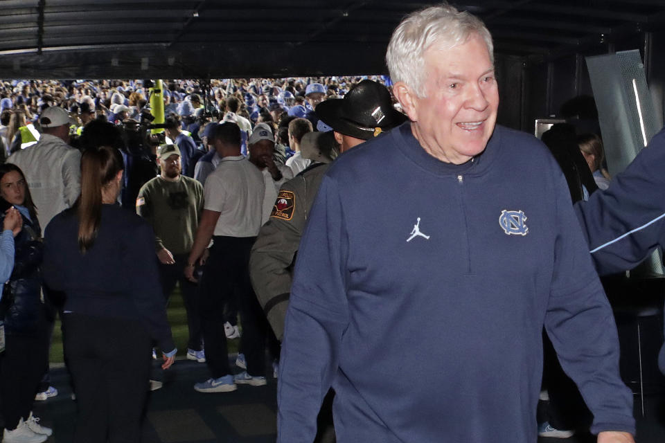 North Carolina coach Mack Brown smiles as he leaves the playing field as fans rush the field behind him after North Carolina defeated rival Duke in two overtimes in an NCAA college football game Saturday, Nov. 11, 2023, in Chapel Hill, N.C. (AP Photo/Chris Seward)