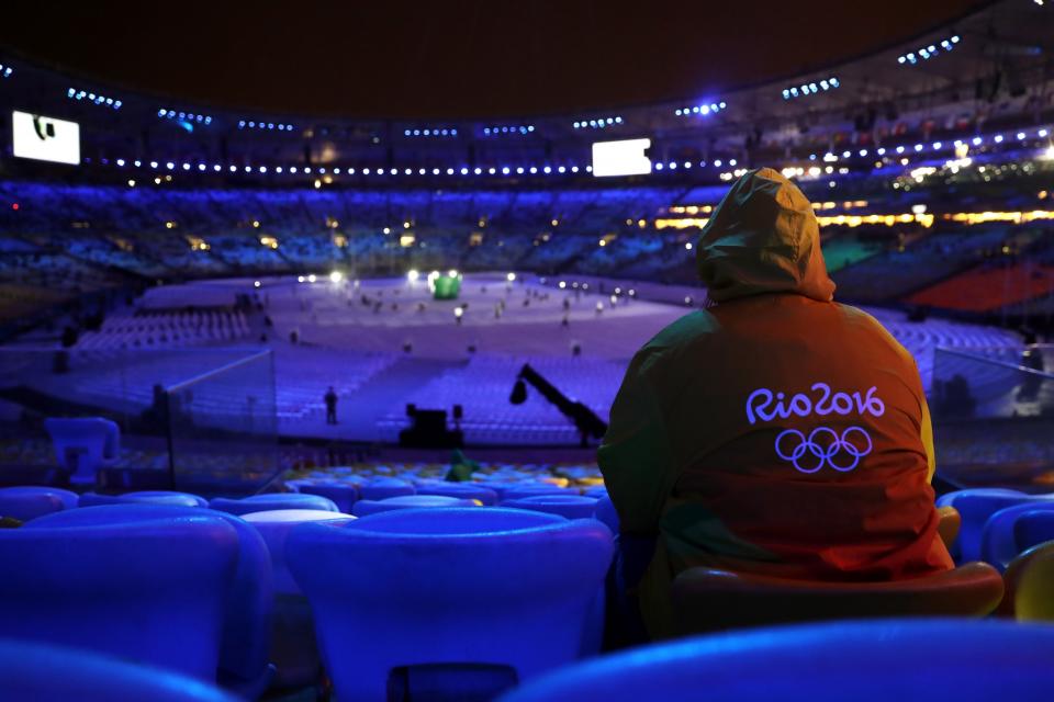 <p>A volunteer shelters from the rain in the stand prior to the Closing Ceremony on Day 16 of the Rio 2016 Olympic Games at Maracana Stadium on August 21, 2016 in Rio de Janeiro, Brazil. (Photo by Alexander Hassenstein/Getty Images) </p>