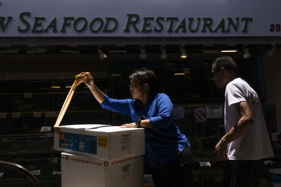 Restaurant workers open up a parcel of abalone from South Africa bought at the Aberdeen Wholesale Fish Market in Hong Kong, Thursday, June 29, 2023. (AP Photo/Louise Delmotte)