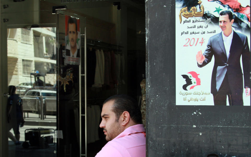 A Syrian man sits near campaign posters of the June 3 presidential election in Damascus, Syria, Monday, May 12, 2014. The Arabic on the poster reads, "Yes, the world cannot change Assad, but Assad will change the world, 2014." On billboards and in posters taped to car windows, new portraits of President Bashar Assad filled the streets of Damascus on Sunday as Syria officially opened its presidential campaign despite a crippling civil war that has devastated the country and left large chunks of territory outside of government control. Assad faces two other candidates in the race: Maher Hajjar and Hassan al-Nouri, both members of the so-called internal opposition tolerated by the government. (AP Photo)