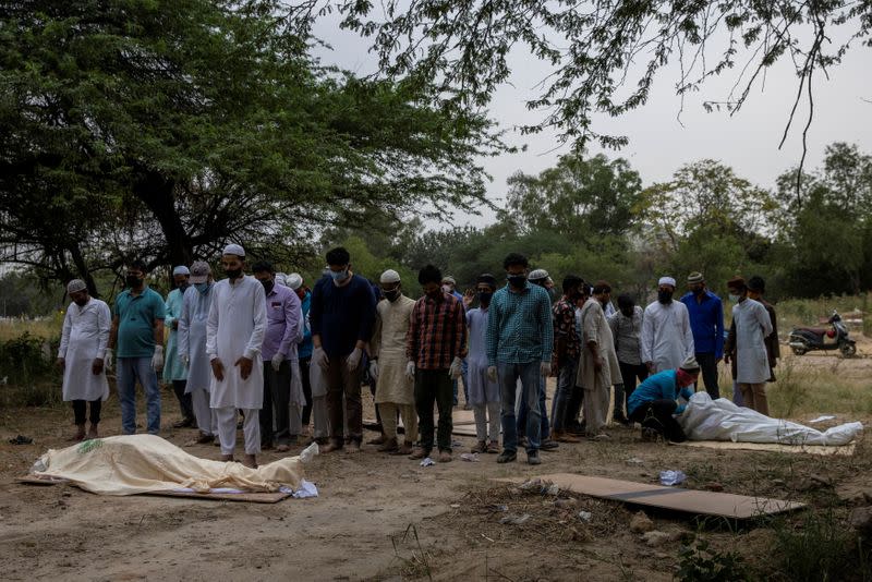 People bury the bodies of COVID-19 victims in New Delhi