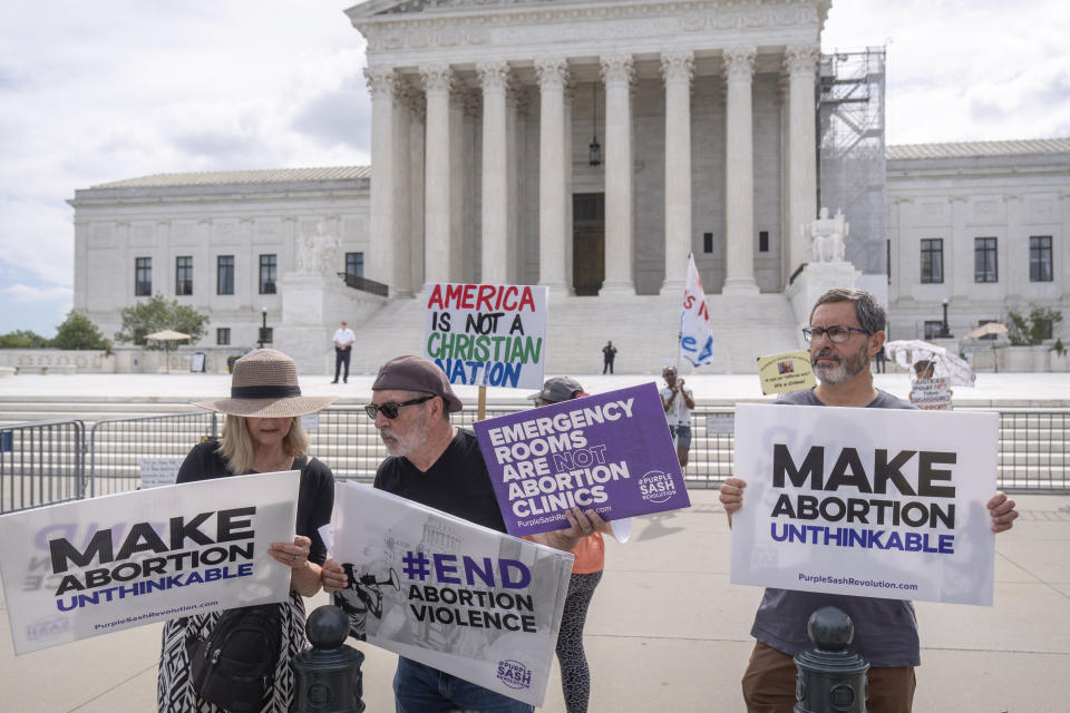 Katie Mahoney, left, and Rev. Patrick Mahoney, chief strategy officer for Stanton Healthcare, an Idaho-based pregnancy center that does not provide abortions, read the text of a Supreme Court decision outside the Supreme Court on Thursday, June 27, 2024, in Washington. The Supreme Court cleared the way Thursday for Idaho hospitals to provide emergency abortions for now in a procedural ruling that left key questions unanswered and could mean the issue ends up before the conservative-majority court again soon. At right is supporter Kevin Krueger. (AP Photo/Mark Schiefelbein)