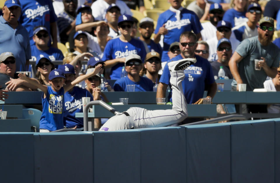 Colorado Rockies' David Dahl dives into the stands to catch a fly ball hit by Los Angeles Dodgers' Yasmani Grandal during the second inning of a tiebreaker baseball game, Monday, Oct. 1, 2018, in Los Angeles. (AP Photo/Jae C. Hong)