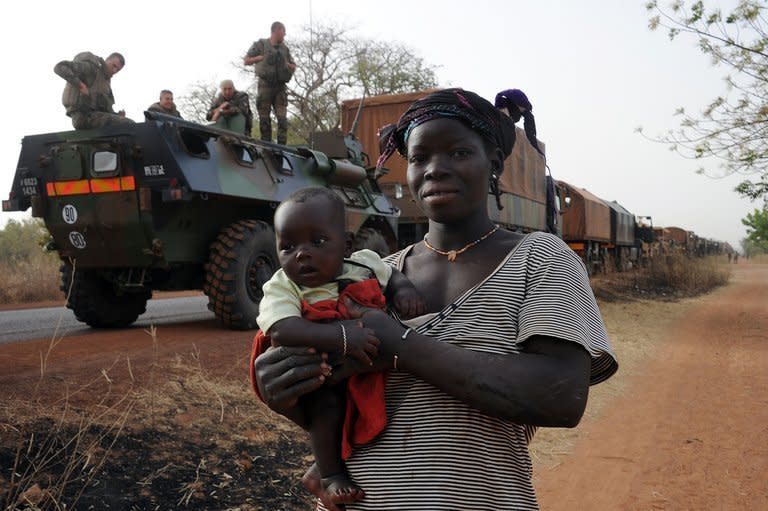 A Malian woman carries her child as she walks by a convoy of French army vehicules arriving in Sevare, in the Mopti region of Mali, on February 1, 2013