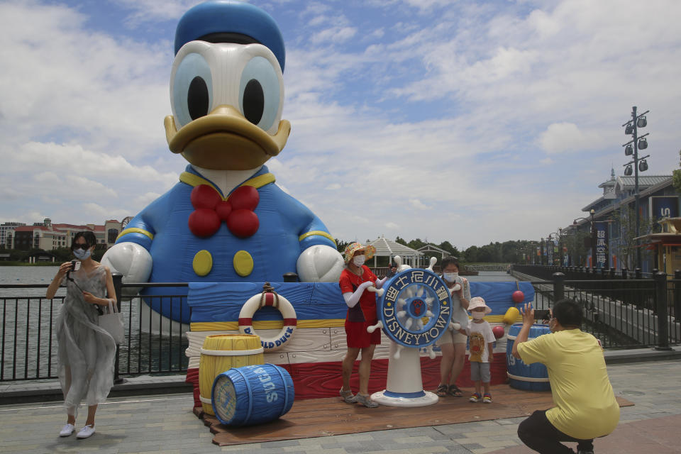 FILE - Visitors pose for photos outside the Disney Resort theme park, Thursday, June 30, 2022, in Shanghai. Last year was a roller coaster ride for theme parks and museums worldwide, with some places approaching pre-pandemic levels and others like parks in China struggling with lockdowns, according to a new report. (AP Photo/Chen Si, File)