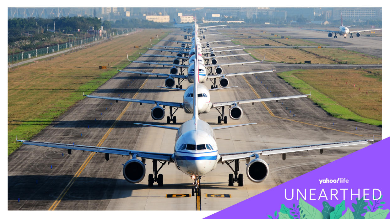 Multiple jets sit in a long, straight line on a runway.