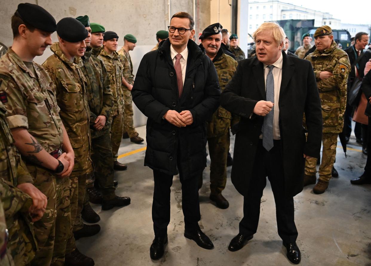 Britain's Prime Minister Boris Johnson (centre right) gestures as he speaks with British troops during a visit with Polish Prime Minister Mateusz Morawiecki (C) to Warszawska Brygada Pancerna military base near Warsaw, Poland on February 10, 2022. (Photo by Daniel LEAL / POOL / AFP) (Photo by DANIEL LEAL/POOL/AFP via Getty Images)