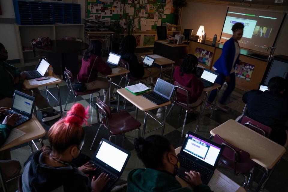 Samantha Koonce Gaines, the Thurgood Marshall Academy Public Charter High School Science Department chair and biology teacher, helps students with questions and encouragement during the physics class taught virtually by physics instructor Rachel Pomeroy, on screen, in May.