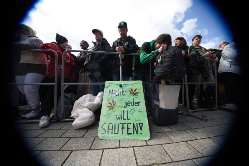 People hold a sign reads "Not everyone wants to drink" at the rally and festival for the legalization of cannabis at the Brandenburg Gate. Paul Zinken/dpa