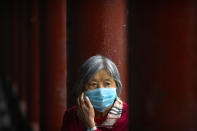 A woman wearing a face mask to protect against the coronavirus sits along a covered walkway at the Temple of Heaven in Beijing, Thursday, Oct. 1, 2020. Millions of Chinese tourists usually would use their week-long National Day holidays to travel abroad. This year, travel restrictions due to the coronavirus pandemic mean that some 600 million tourists - about 40% of the population - will travel within China during the holiday that began Thursday, according to Ctrip, China's largest online travel agency. (AP Photo/Mark Schiefelbein)