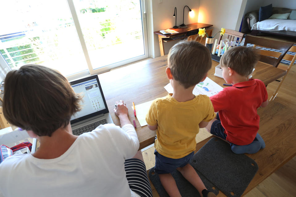 17 April 2020, Bavaria, Kaufbeuren: ILLUSTRATION - The mother of six-year-old Jakob and four-year-old Valentin works at home on a laptop while her children paint and look at a book next to her. In the Corona crisis, more parents will be entitled to emergency care for younger children - but for the time being there will be no uniform nationwide regulation. Photo: Karl-Josef Hildenbrand/dpa (Photo by Karl-Josef Hildenbrand/picture alliance via Getty Images)