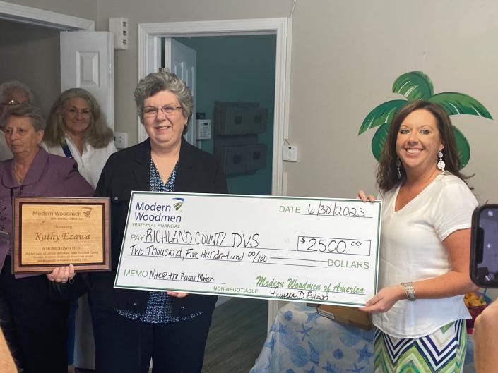 Kathy Ezawa, executive director of the Richland County Domestic Violence Shelter, center, accepts a donation for the nonprofit agency from Modern Woodmen at her retirement celebration.