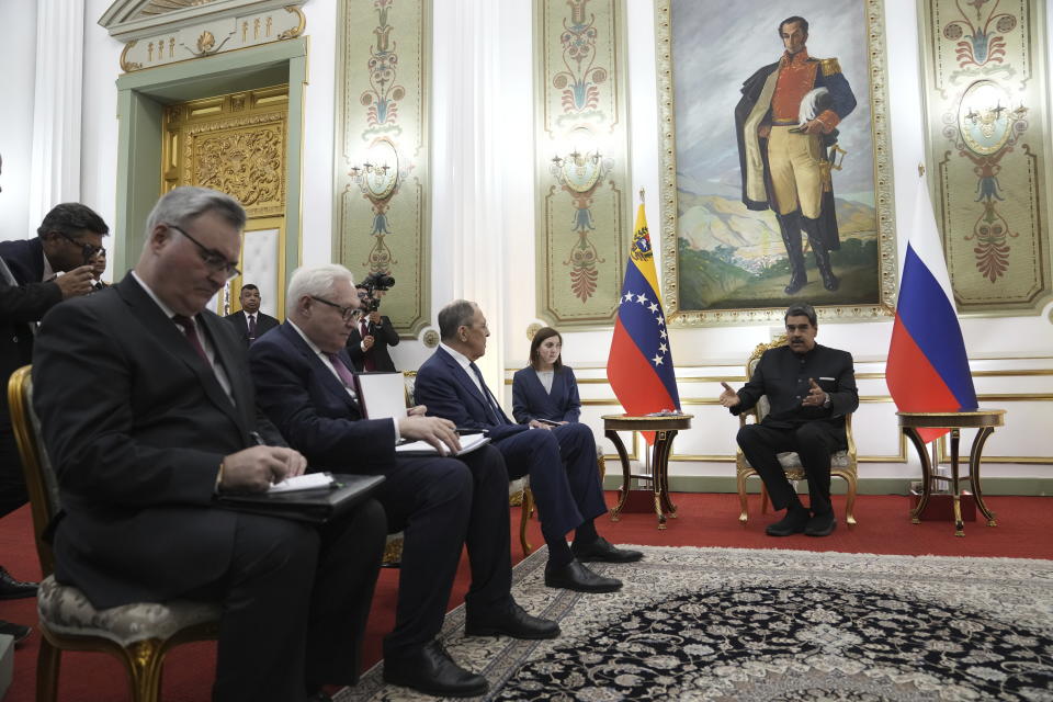 Venezuelan President Nicolas Maduro, right, meets with Russia's Foreign Minister Sergey Lavrov, third from right, at Miraflores presidential palace in Caracas, Venezuela, Tuesday, Feb. 20, 2024. Behind is a painting of Simon Bolivar, Venezuela's independence hero. (AP Photo/Ariana Cubillos)