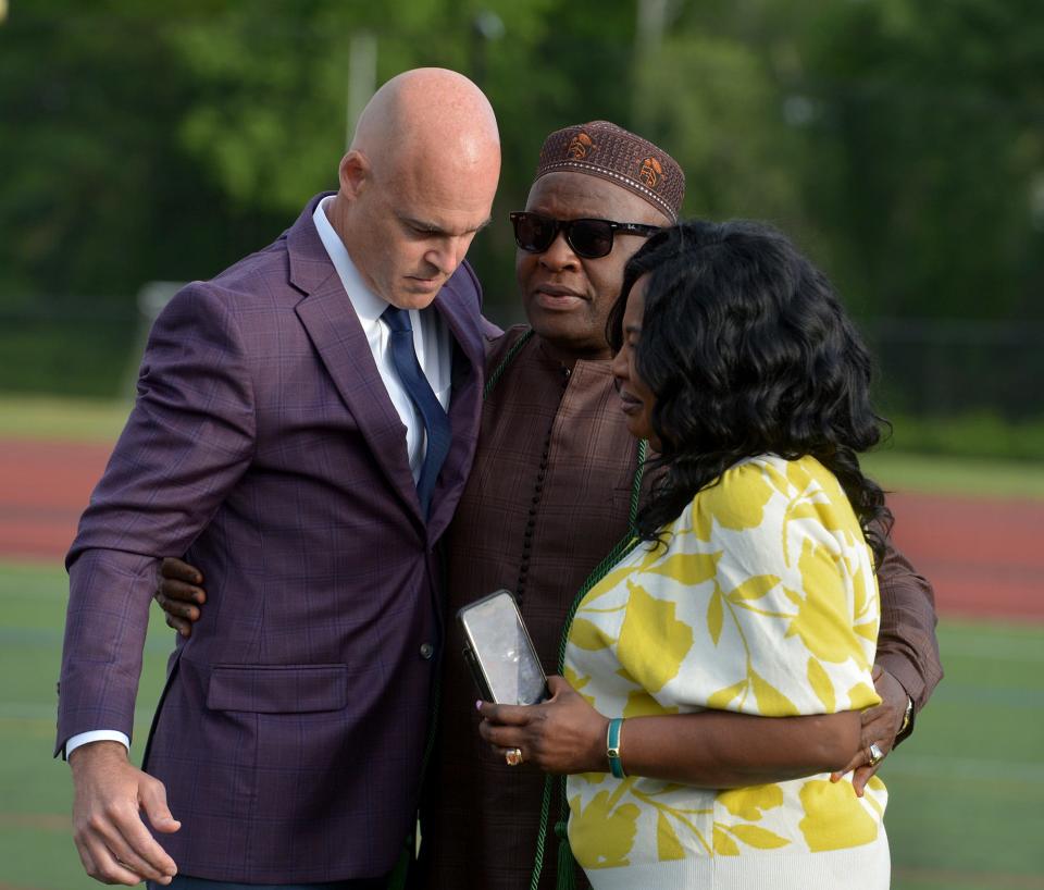 Natick High School Principal Brian Harrigan hugs George and Caroline Taboh, parents of Giovanni Taboh, during graduation at Memorial Field, June 3, 2022.  Giovanni died in a March 6, 2021 car accident. 