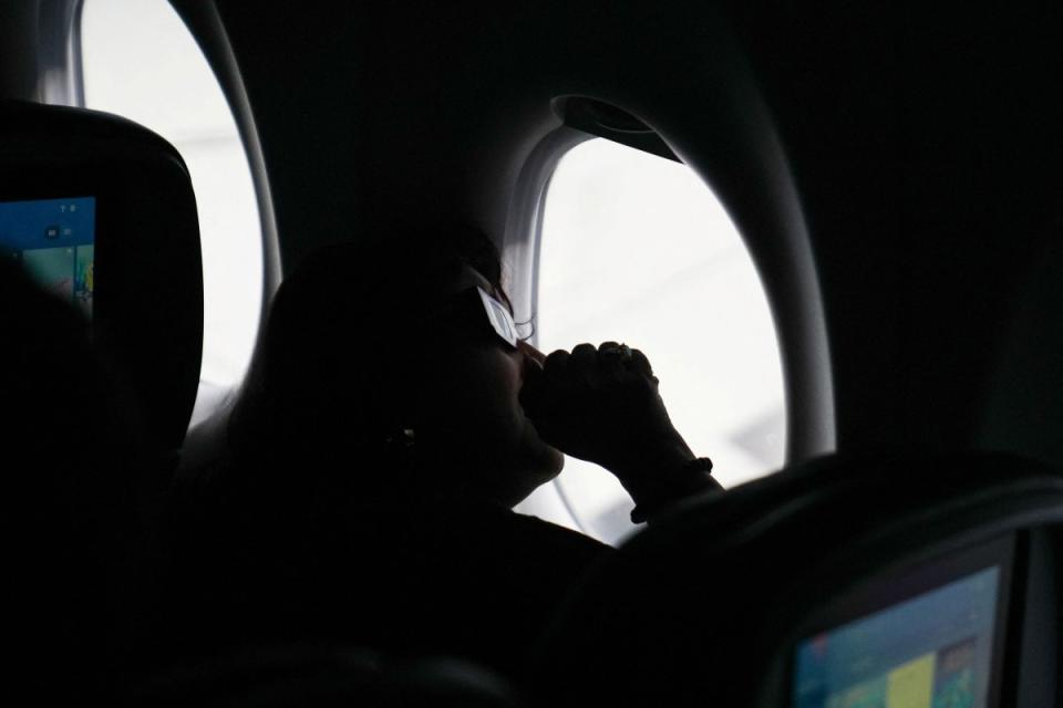 A passenger wears solar eclipse glasses as she looks from a special Delta Airlines eclipse flight following the path of totality over the United States.<span class="copyright">Leonardo Benassatto—Reuters</span>