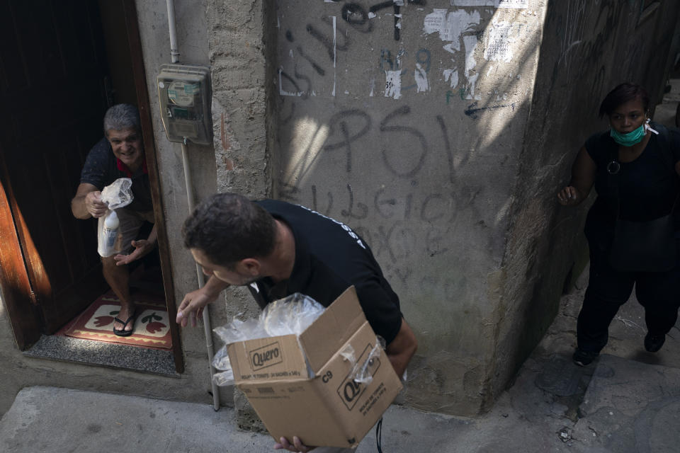 Wallace da Silva, president of the residents association, gives a pack with soap and detergent to a resident in an effort to avoid the spread of the new coronavirus in the Rocinha slum in Rio de Janeiro, Brazil, Tuesday, March 24, 2020. (AP Photo/Leo Correa)