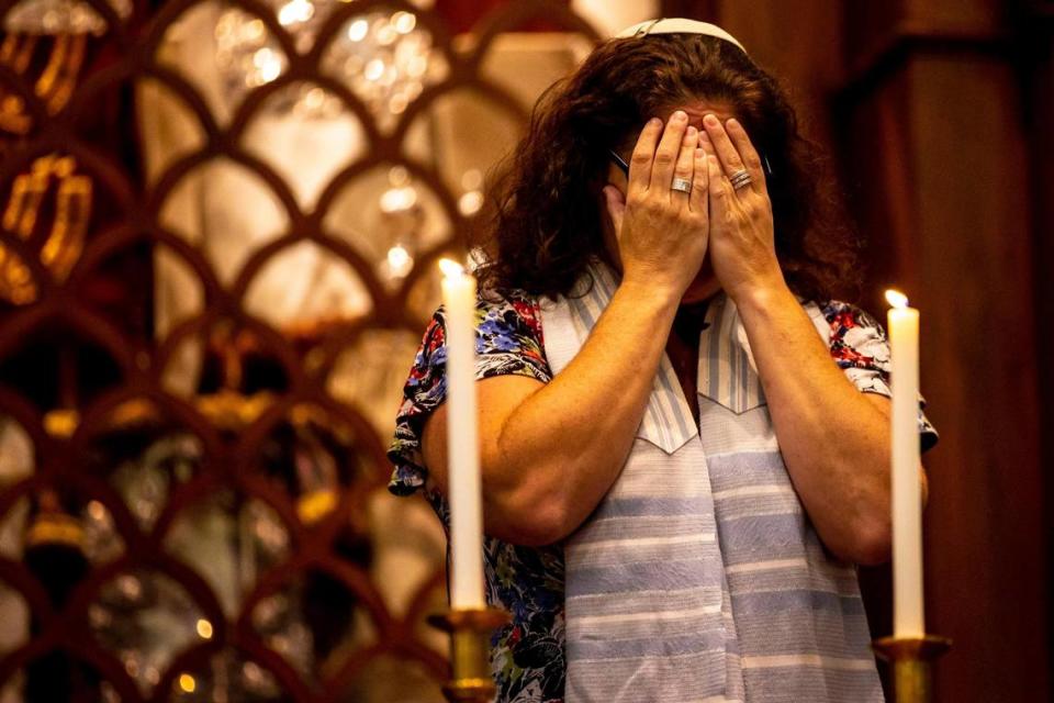 La rabina Amy Morrison se cubre los ojos mientras recita la bendición sobre las velas de Shabat durante el servicio en el Temple Israel of Greater Miami en Miami, Florida, el viernes 11 de marzo de 2022.