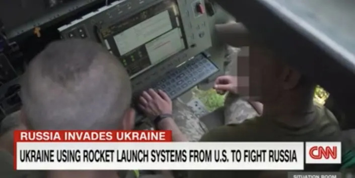 A still from CNN footage showing two Ukrainian soldiers inside a HIMARS truck, showing them operating its system