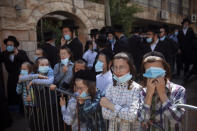 Ultra-Orthodox Jews, followers of the Hasidic sect of Shomrei Emunim, wearing protective face masks amid concerns over the country's coronavirus outbreak, gather for the funeral of their Rabbi Refael Aharon Roth, 72, who died from the virus, in Bnei Brak, Israel, Thursday, Aug. 13, 2020. (AP Photo/Oded Balilty)