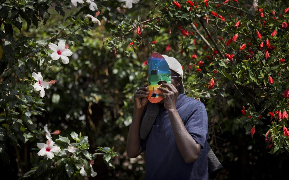 A protester prepares his mask to preserve his anonymity as Kenyan gays and lesbians and others supporting their cause stage a rare protest, against Uganda's increasingly tough stance against homosexuality and in solidarity with their counterparts there, outside the Uganda High Commission in Nairobi, Kenya Monday, Feb. 10, 2014. Homosexuality has been criminalized in Uganda where lawmakers have recently passed a new bill, which appears to have wide support among Ugandans, that prescribes life imprisonment for "aggravated" homosexual acts. (AP Photo/Ben Curtis)