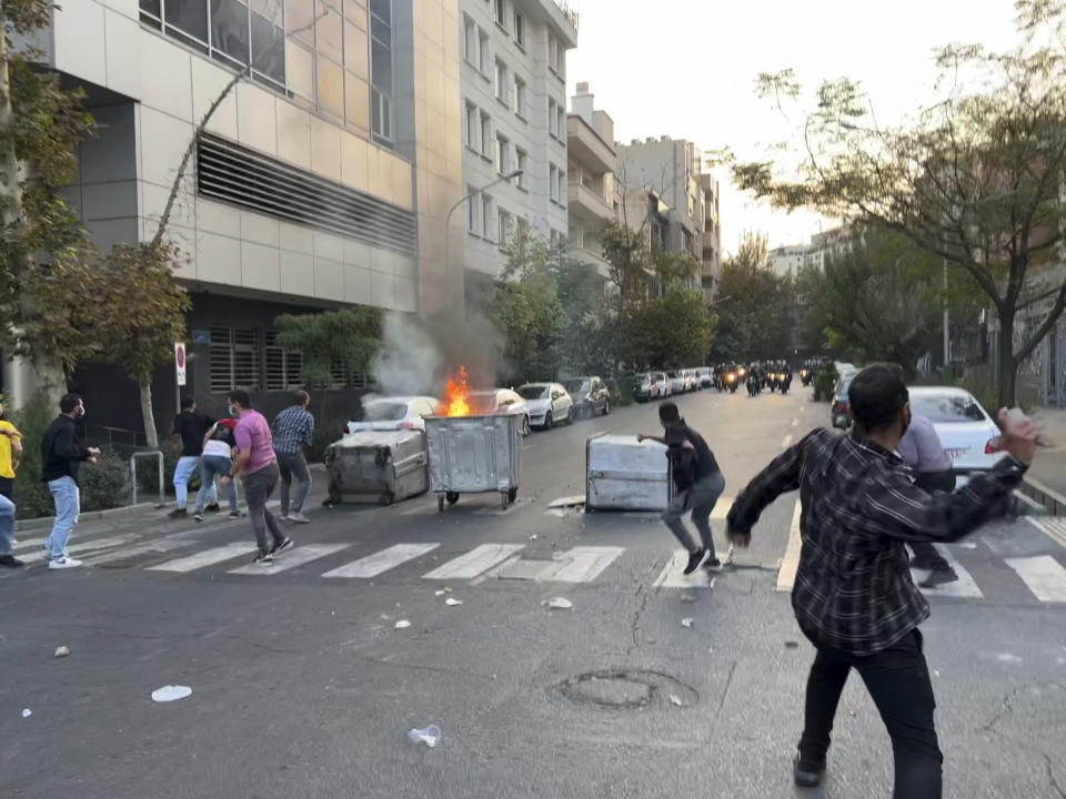 In this Tuesday, Sept. 20, 2022, photo taken by an individual not employed by the Associated Press and obtained by the AP outside Iran, protesters throw stones at anti-riot police during a protest over the death of a young woman who had been detained for violating the country's conservative dress code, in downtown Tehran, Iran. Iran faced international criticism on Tuesday over the death of a woman held by its morality police, which ignited three days of protests, including clashes with security forces in the capital and other unrest that claimed at least three lives. (AP Photo)