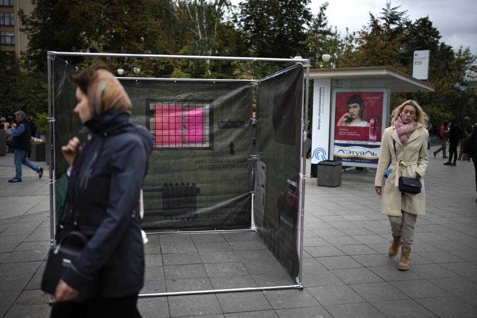 People walk past a campaign stand in Moscow, Russia, Tuesday, Sept. 7, 2021, for Andrei Pivovarov, an opposition activist who was jailed earlier this year but is allowed to run in the upcoming election for the State Duma, the lower house of the Russian parliament. Russia is holding three days of voting, ending Sunday, Sept. 19, 2021, for a new parliament that is unlikely to change the country’s political complexion. (AP Photo/Alexander Zemlianichenko)