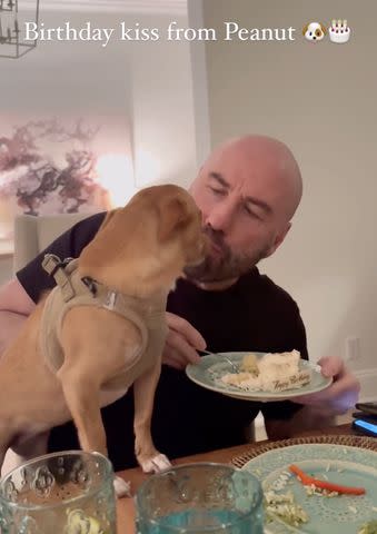 <p>John Travolta/Instagram</p> John Travolta receives a birthday kiss from his dog Peanut