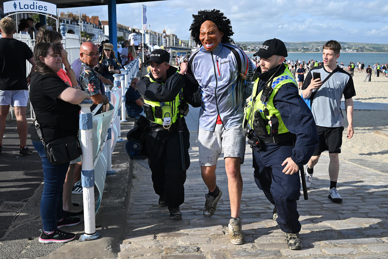 Police officers detain a protester wearing a mask 