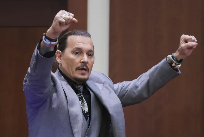 Actor Johnny Depp demonstrates what he claims was an alleged attack by his ex-wife Amber Heard, as he testifies during the trial at the Fairfax County Circuit Court in Fairfax, Va., Wednesday, April 20, 2022. Actor Johnny Depp sued his ex-wife Amber Heard for libel in Fairfax County Circuit Court after she wrote an op-ed piece in The Washington Post in 2018 referring to herself as a "public figure representing domestic abuse." (Evelyn Hockstein/Pool via AP)