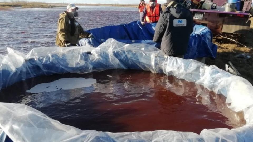 Personal intenta contener el agua contaminada con diésel.