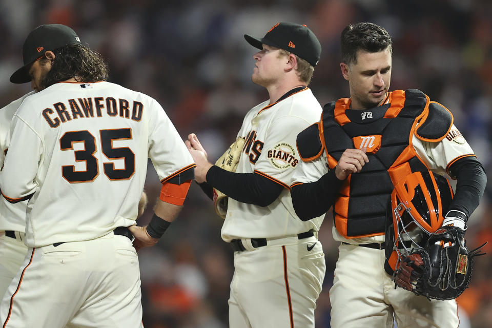 San Francisco Giants pitcher Logan Webb, middle, meets on the mound with shortstop Brandon Crawford (35) and catcher Buster Posey during the fourth inning of Game 5 of a baseball National League Division Series against the Los Angeles Dodgers Thursday, Oct. 14, 2021, in San Francisco. (AP Photo/John Hefti)