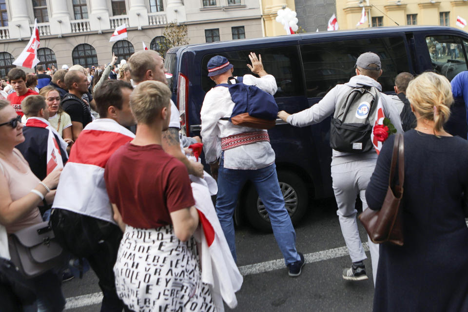 Belarusian opposition supporters surround a police bus during their rally in the center of Minsk, Belarus, Sunday, Aug. 30, 2020. Opposition supporters whose protests have convulsed the country for two weeks aim to hold a march in the capital of Belarus. (AP Photo)