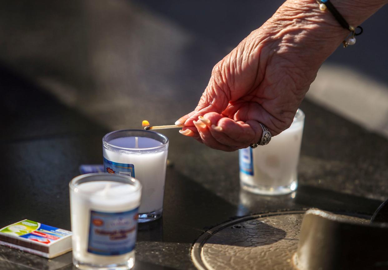 Holocaust survivor Rickie Taras lights a candle to honor the memory of the millions of men, women and children killed in the holocaust during the International Holocaust Remembrance Day ceremony at Civic Center Park in Palm Desert, Calif., Thursday, Jan. 27, 2022.