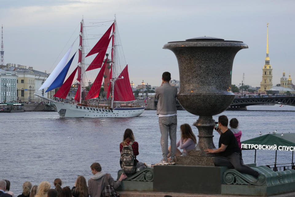 People watch a brig with scarlet sails makes its way down the Neva River during a rehearsal for the Scarlet Sails festivities marking school graduation in St. Petersburg, Russia, Thursday, June 23, 2022. (AP Photo/Dmitri Lovetsky)