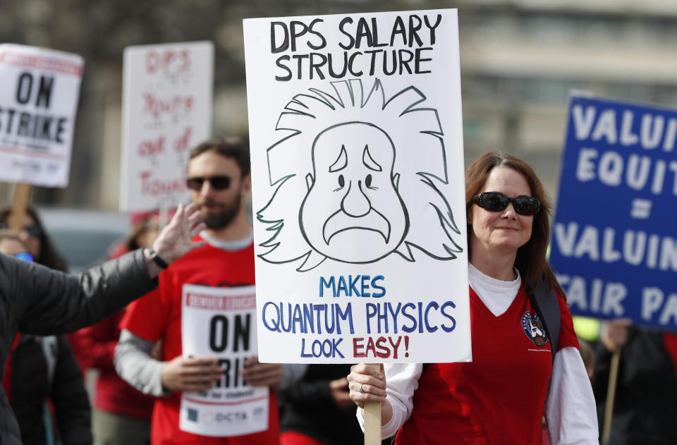 An instructor carries a placard as she marches to Denver Public Schools headquarters to deliver Valentine Day cards Wednesday, Feb. 13, 2019, in Denver. Teachers walked off their jobs Monday, the first strike by teachers in Denver in 25 years. (AP Photo/David Zalubowski)