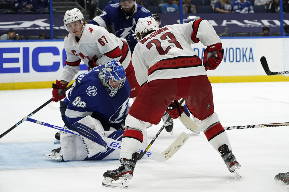 Tampa Bay Lightning goaltender Andrei Vasilevskiy (88)makes a save as Carolina Hurricanes left wing Brock McGinn (23) and center Morgan Geekie (67) look for a rebound during the third period in Game 4 of an NHL hockey Stanley Cup second-round playoff series Saturday, June 5, 2021, in Tampa, Fla. (AP Photo/Chris O'Meara)