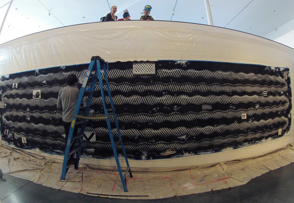 In this Friday, Feb. 15, 2013 photo, patrons look from above as Ryan Travis Christian applies charcoal to a wall installation at the Contemporary Art Museum in Raleigh, N.C. The Chicago artist completely reworked the wall-sized drawing several days into his first museum exhibition. (AP Photo/Allen Breed)