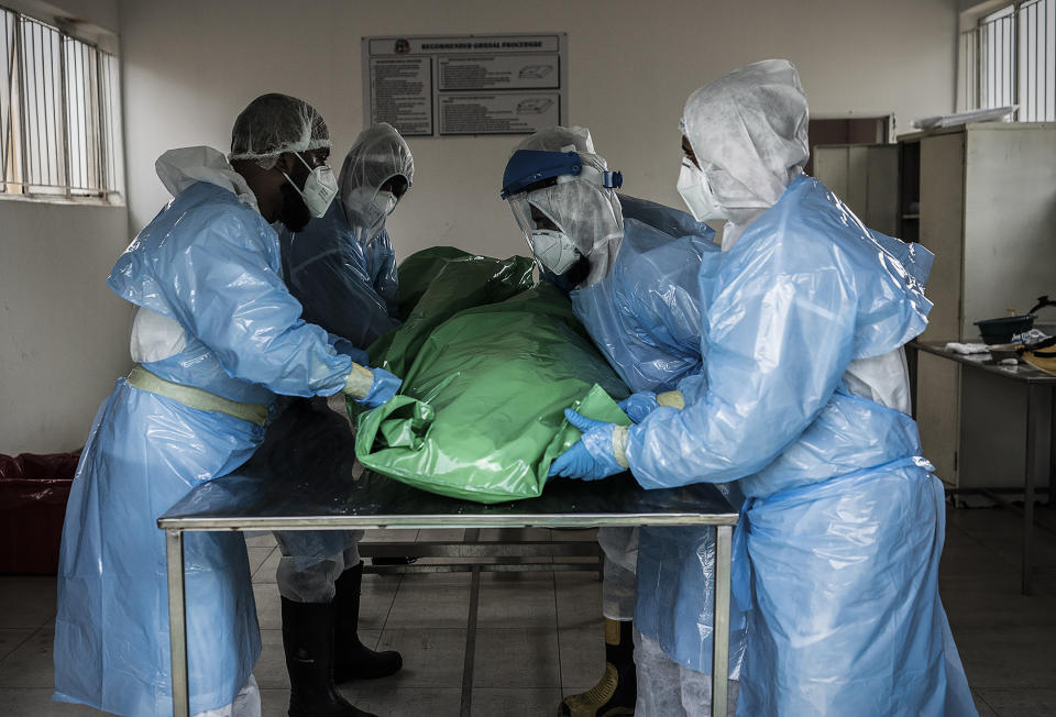 Members of the Saaberie Chishty Burial Society prepare the body of a person who died from COVID-19 at the Avalon Cemetery in Lenasia, Johannesburg Saturday Dec. 26, 2020. South Africa’s health minister has announced an “alarming rate of spread” in the country, with more than 14,000 new confirmed coronavirus cases and more than 400 deaths reported Wednesday. It was the largest single-day increase in cases. (AP Photo/Shiraaz Mohamed)
