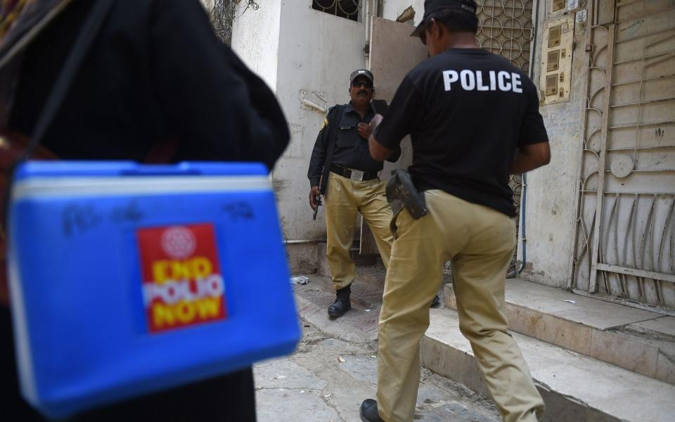Police escort a polio team during a door-to-door vaccination campaign in Karachi - Rizwan TABASSUM/AFP