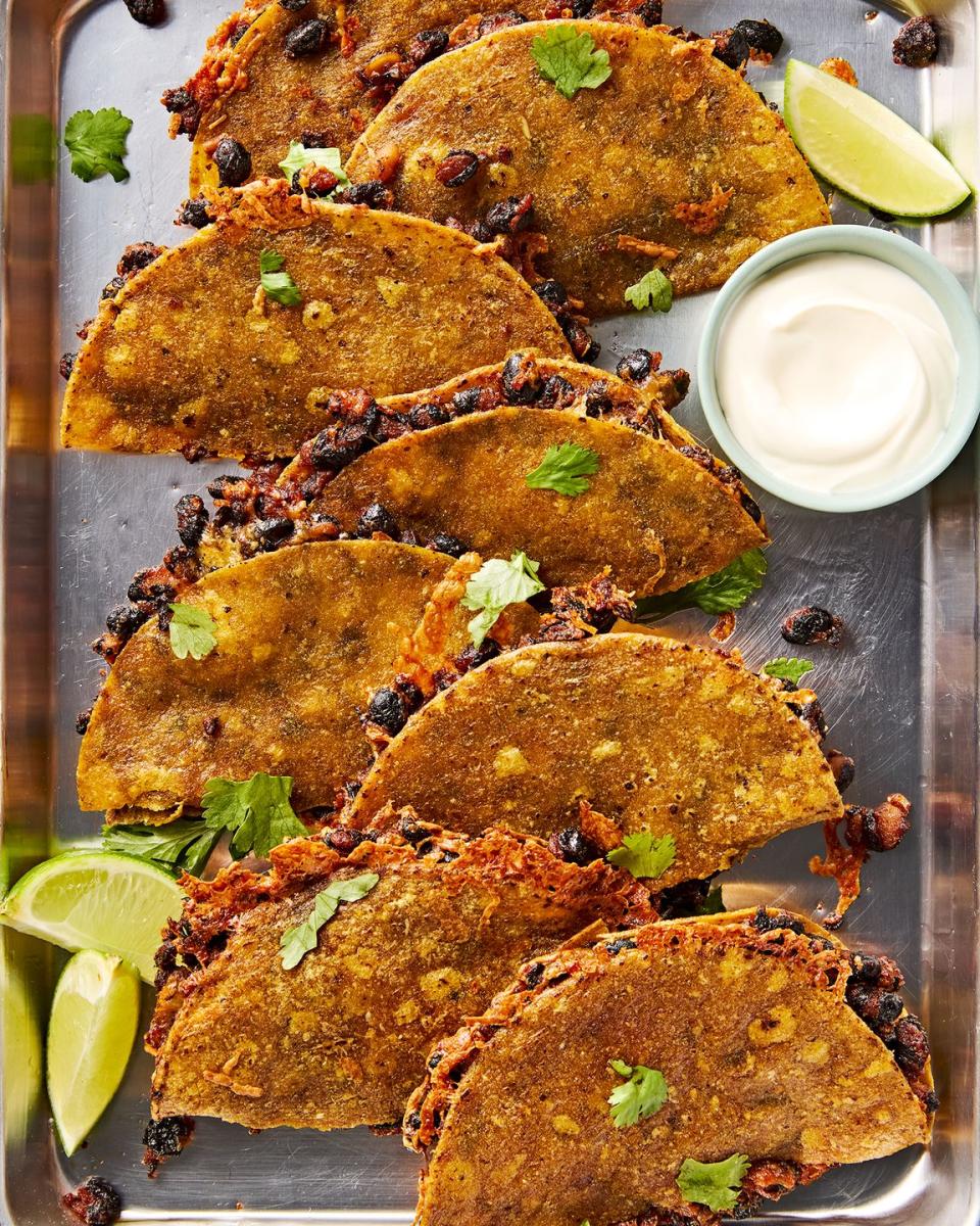 crispy sheet pan black bean tacos on a sheet pan with a bowl of sour cream