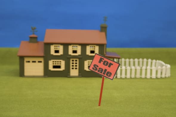 A For Sale sign in front of a model house