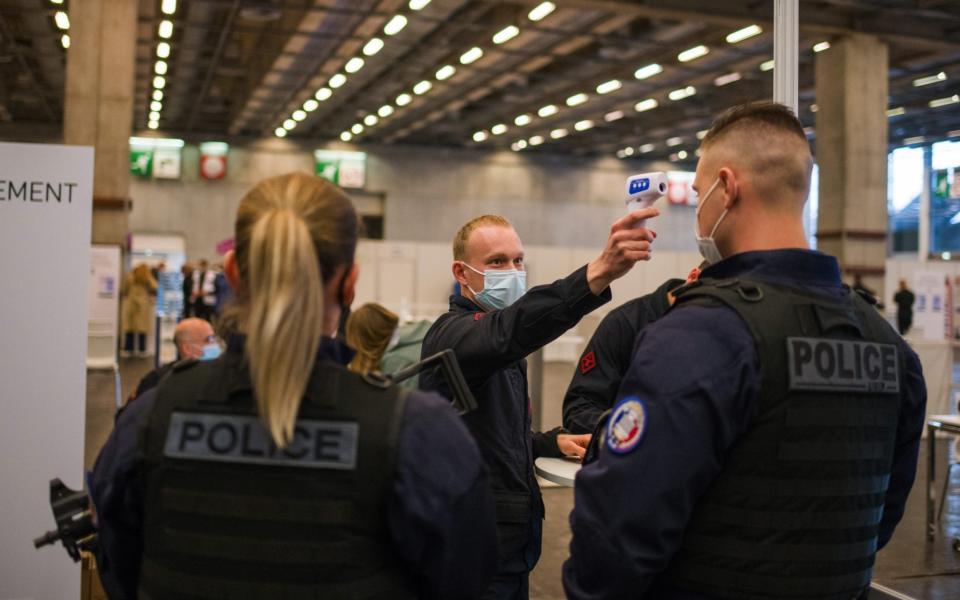 Police officers have their temperatures taken as they arrive at the Covid-19 'vaccinodrome' vaccination site at the Porte de Versailles exhibition center  - Nathan Laine/Bloomberg