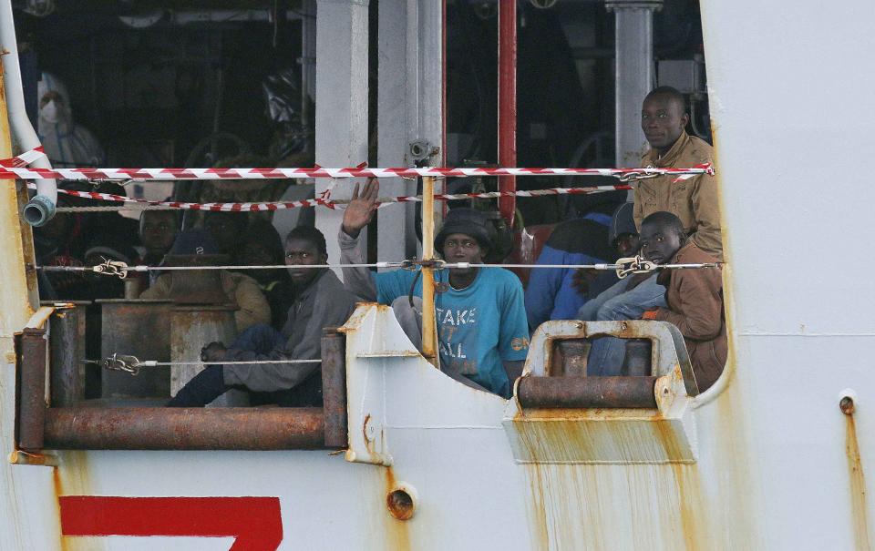 Migrants sit on the Italian Navy patrol ship Spica, as they arrive at the Sicilian harbour of Pozzallo