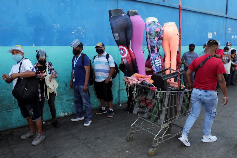 Un hombre pasa vendiendo ropa en un carrito junto a una fila para votar en las elecciones presidenciales y parlamentarias en Lima, Perú.