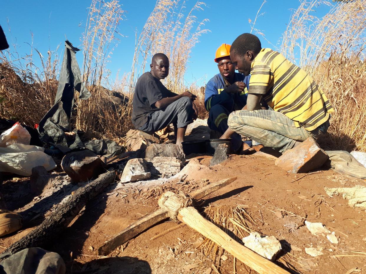 Miners eat lunch on the hill-top gold field of Msasa