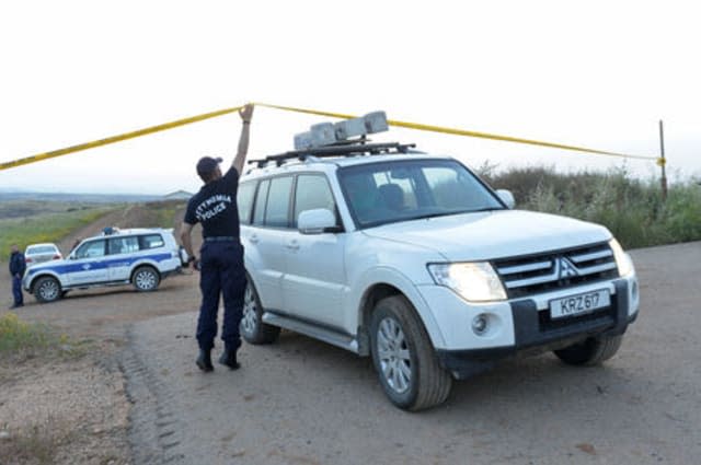Police officers and rescuers are seen at the area where the body of a woman was discovered near the village of Orounta