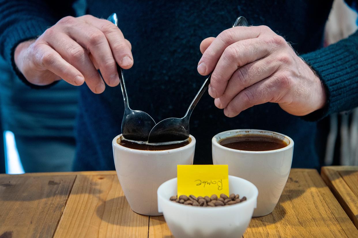 Eli Masem, director of retail and a coffee educator at Cooperative Coffee Roasters, removes coffee grounds from a cup of coffee during a coffee tasting, January 19, 2024.