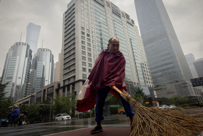 A worker sweeps a street in the Central Business District on a rainy day in Beijing